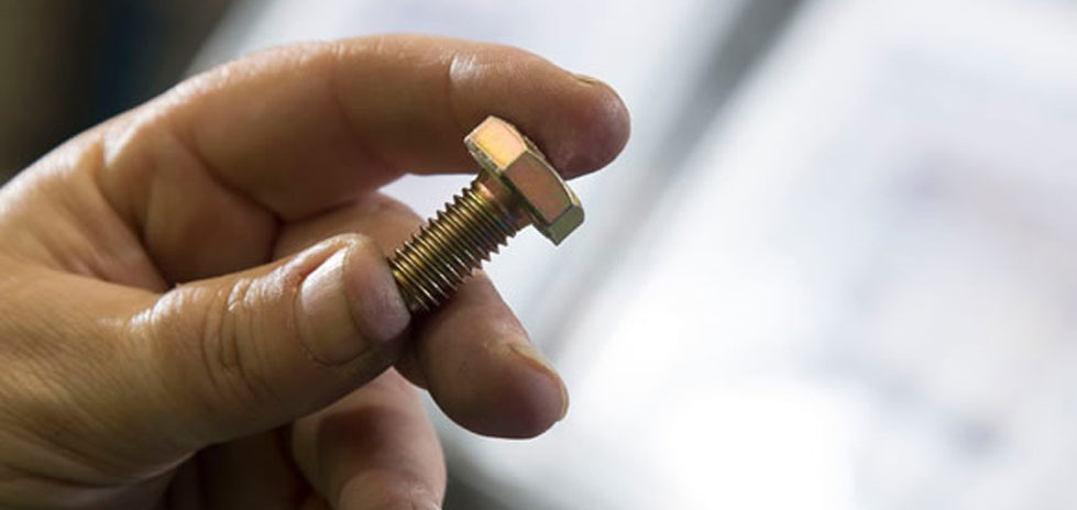 Persons hand holding a bolt between their fingers