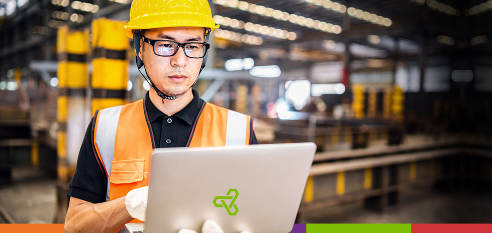 Un hombre con gafas y un casco amarillo mirando una computadora portátil con el logo verde de Optimas