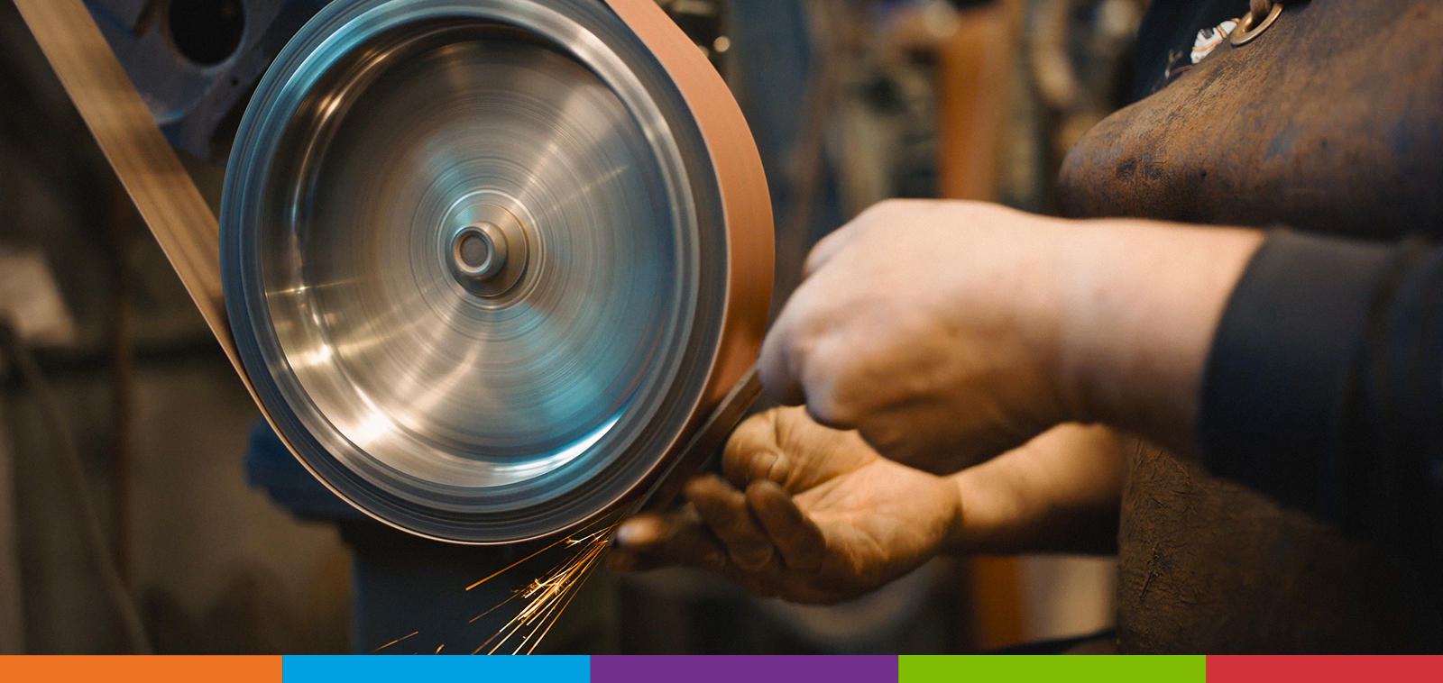 A person sanding a piece of metal on a sanding belt