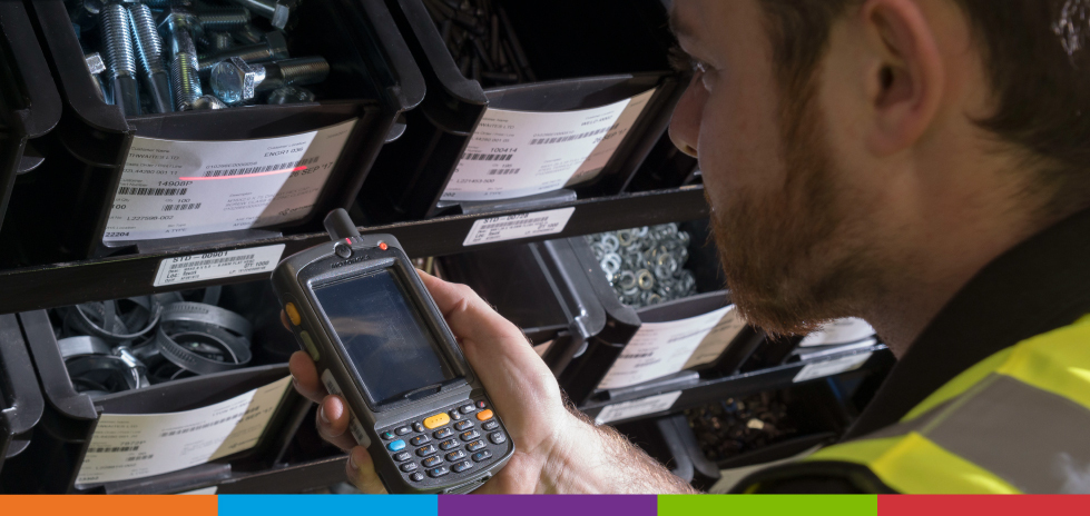 A man looking at bins using a scanner to scan a barcode on one of the bins